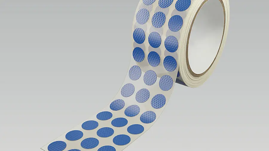 Roll of blue circular die-cut parts on a carrier film